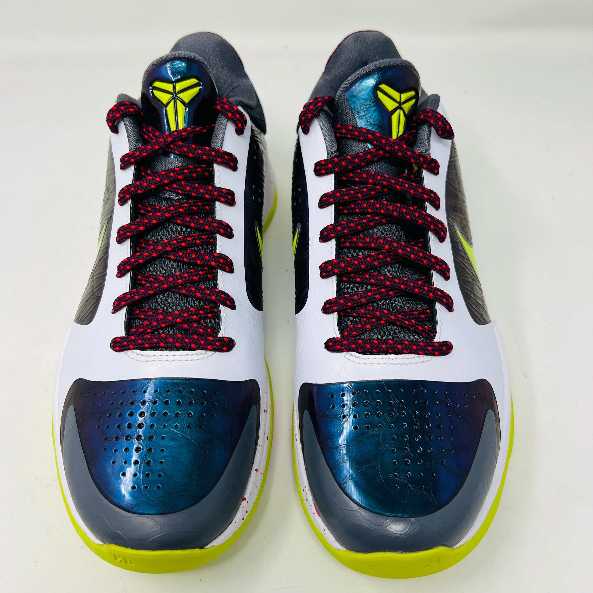 The Nike Kobe 5 Protro Chaos sneaker, authentic and vibrant, is showcased on a black shoe box. It features a bright lime green Nike swoosh, purple and white accents, a speckled pink midsole, red-speckled laces, and a textured gray heel.