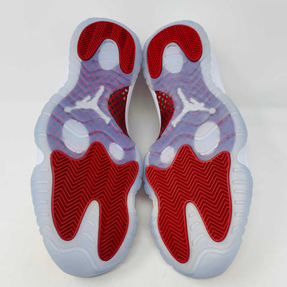 Jordan 11 Retro Cherry 2022 sneakers with red and white colorway, viewed from the bottom showing the red traction pattern.