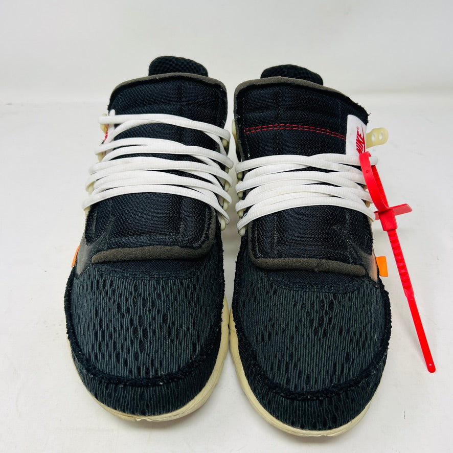 The 2017 classic Nike Air Presto Off-White features a black sneaker with white laces, a red tag, iconic AIR text, and an edgy zip tie. Displayed on its box, it includes extra black, neon green, and orange laces labeled SHOELACES.