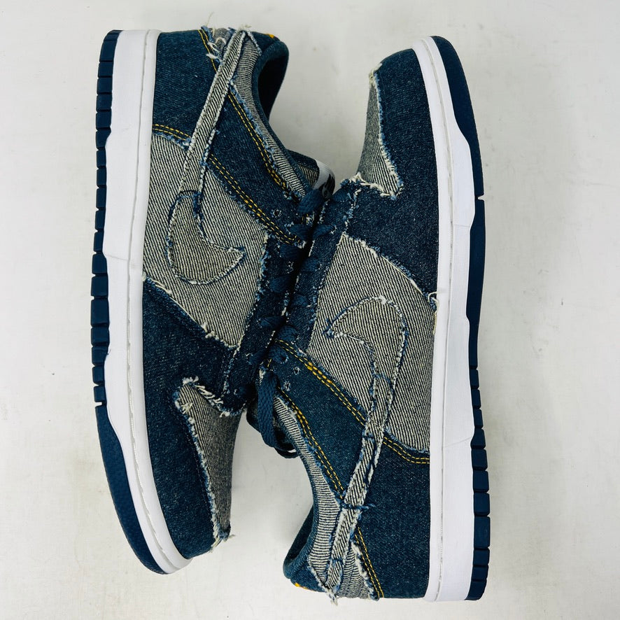 Side view of a brand new Nike Dunk Low CL Denim sneaker with white accents, resting on its orange box. A label reads Denim Dunk. Released in 2006, it features a textured design with a white midsole and blue outsole. Box condition is pristine. Brand: Nike.