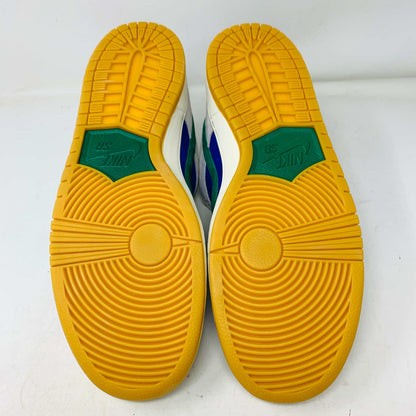 The Nike SB Dunk Low Hyper Royal Malachite, a fresh pair of white and blue sneakers with a green swoosh and gum sole, includes extra laces and is presented atop a purple Nike SB shoe box.