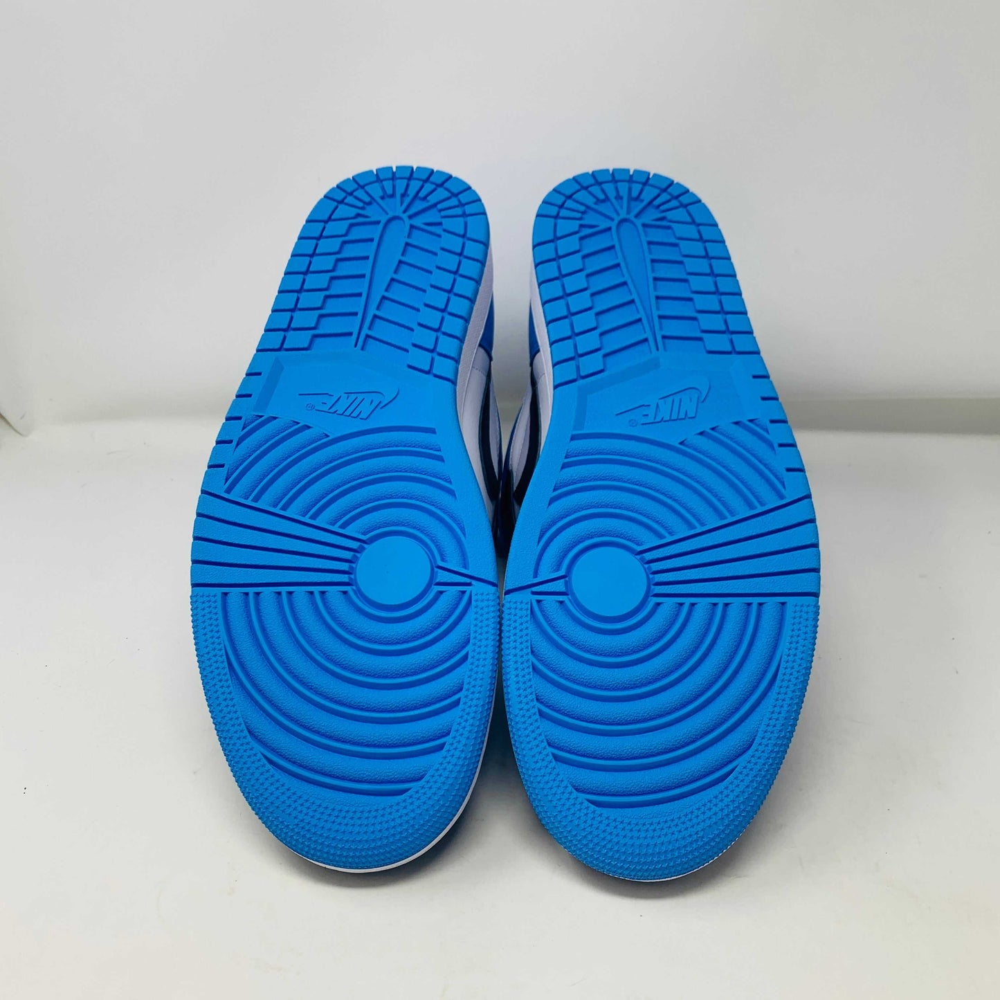 Bottom view of Jordan 1 High UNC Toe sneakers with blue soles.