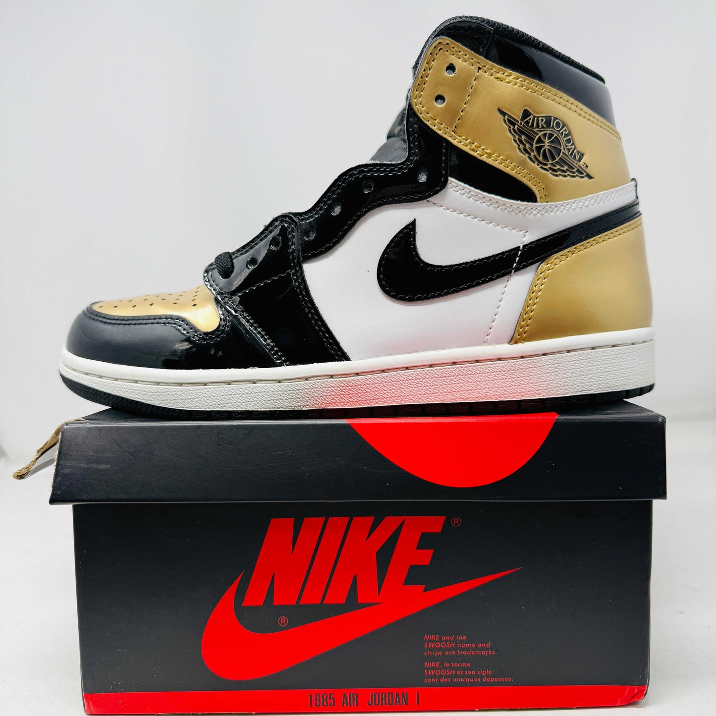 Jordan 1 Retro High NRG sneaker in patent gold toe with black and white accents on Nike box