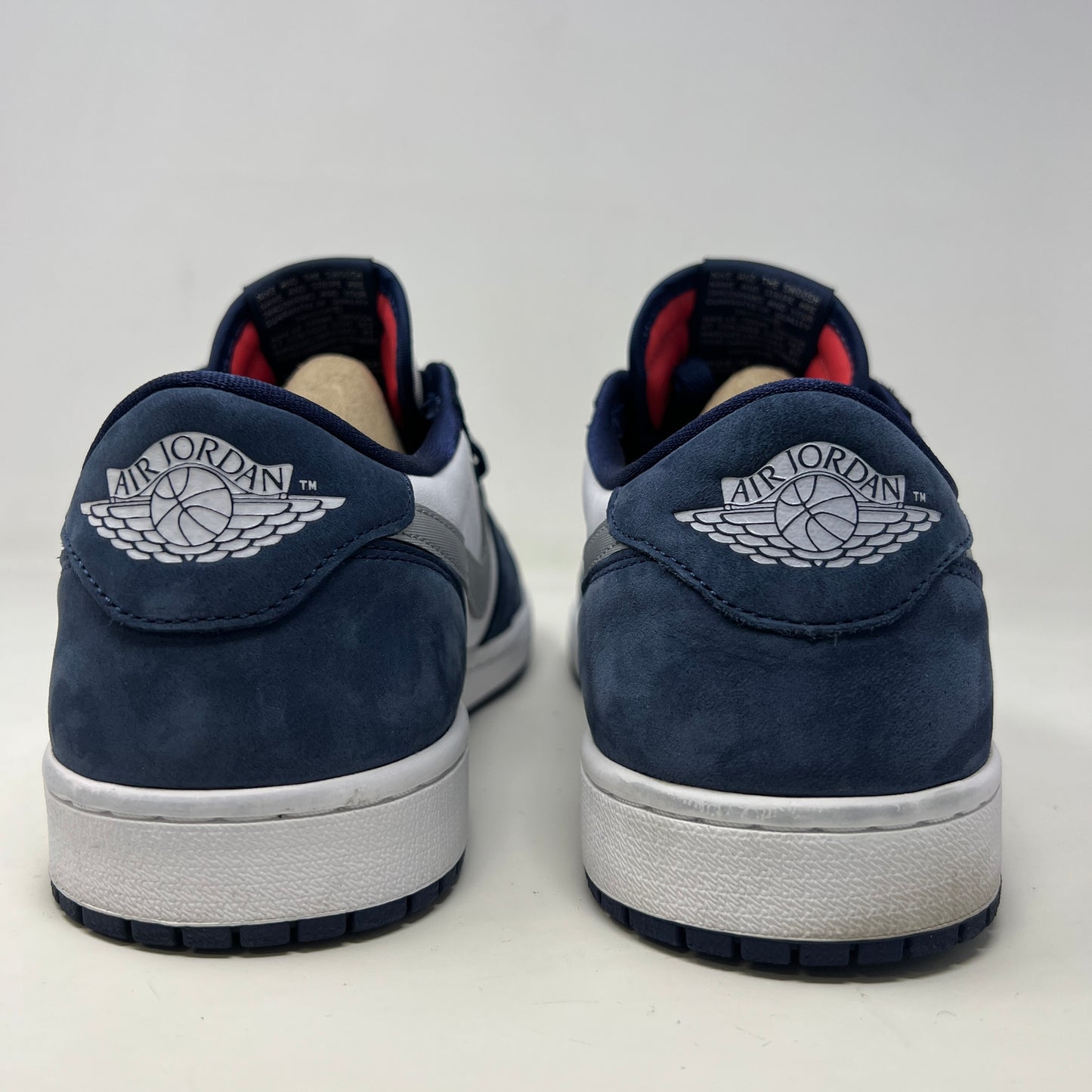 A Jordan 1 Low SB Midnight Navy shoe from Jordan, featuring blue toe and heel, white side panels, and a silver swoosh, is displayed on its box. The VERY CLEAN UPPERS are complemented by the size and product info visible on the label.