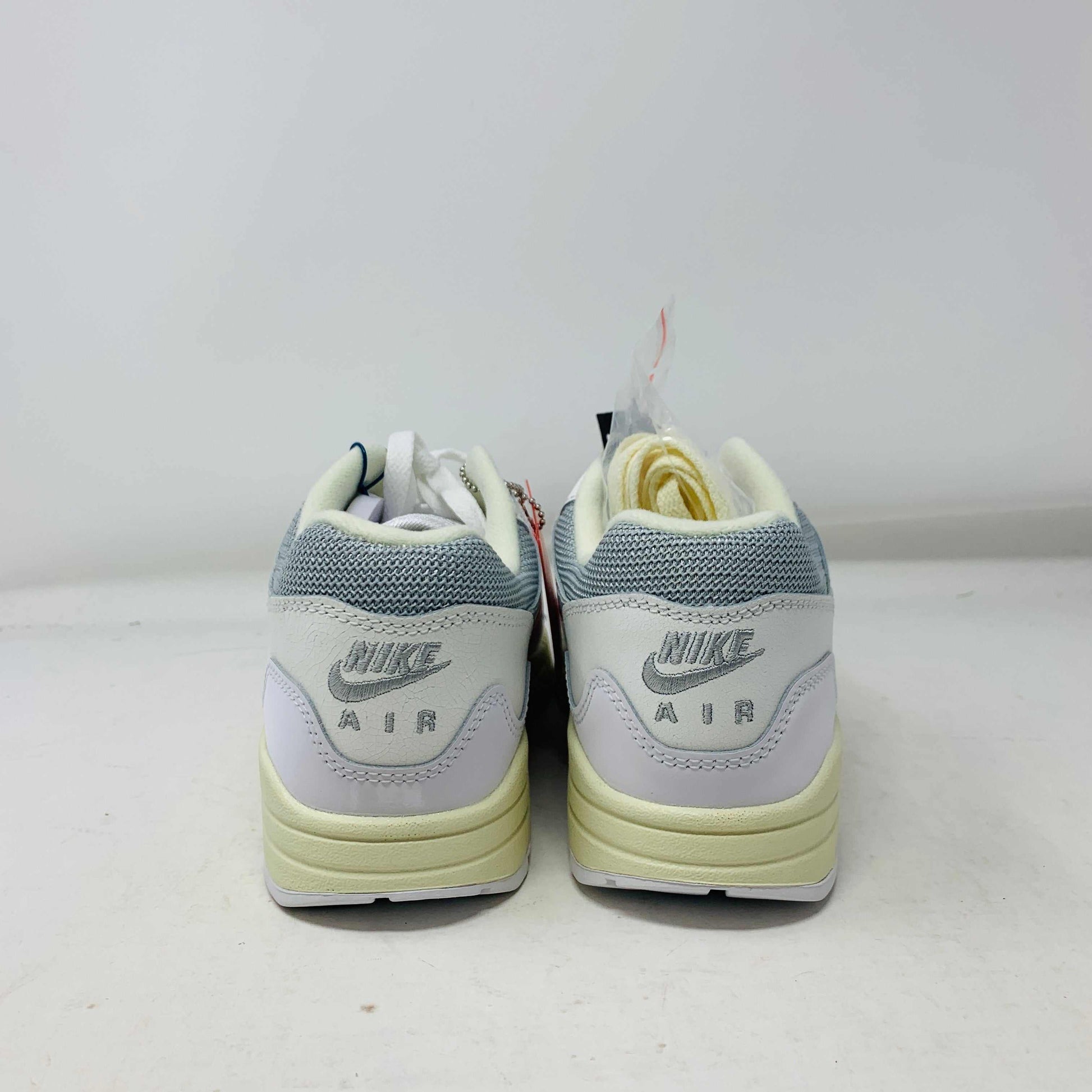 The Nike Air Max 1 Patta Waves White, a brand new sneaker, features a visible air cushion sole and swoosh logo. It comes elegantly displayed on a matching P.G.L.F.A. box with extra laces in a plastic bag attached to the tongue.