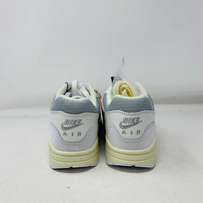 The Nike Air Max 1 Patta Waves White, a brand new sneaker, features a visible air cushion sole and swoosh logo. It comes elegantly displayed on a matching P.G.L.F.A. box with extra laces in a plastic bag attached to the tongue.