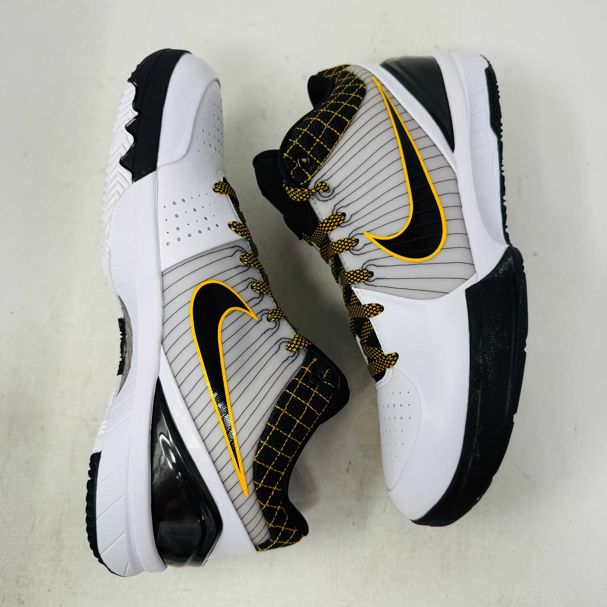 The Nike Kobe 4 Protro White Black Del Sol is a brand-new, authentic Nike sneaker on a shoebox. Predominantly white, it features black and yellow accents with a swoosh logo, a black sole, and yellow-speckled laces, designed for performance and comfort.