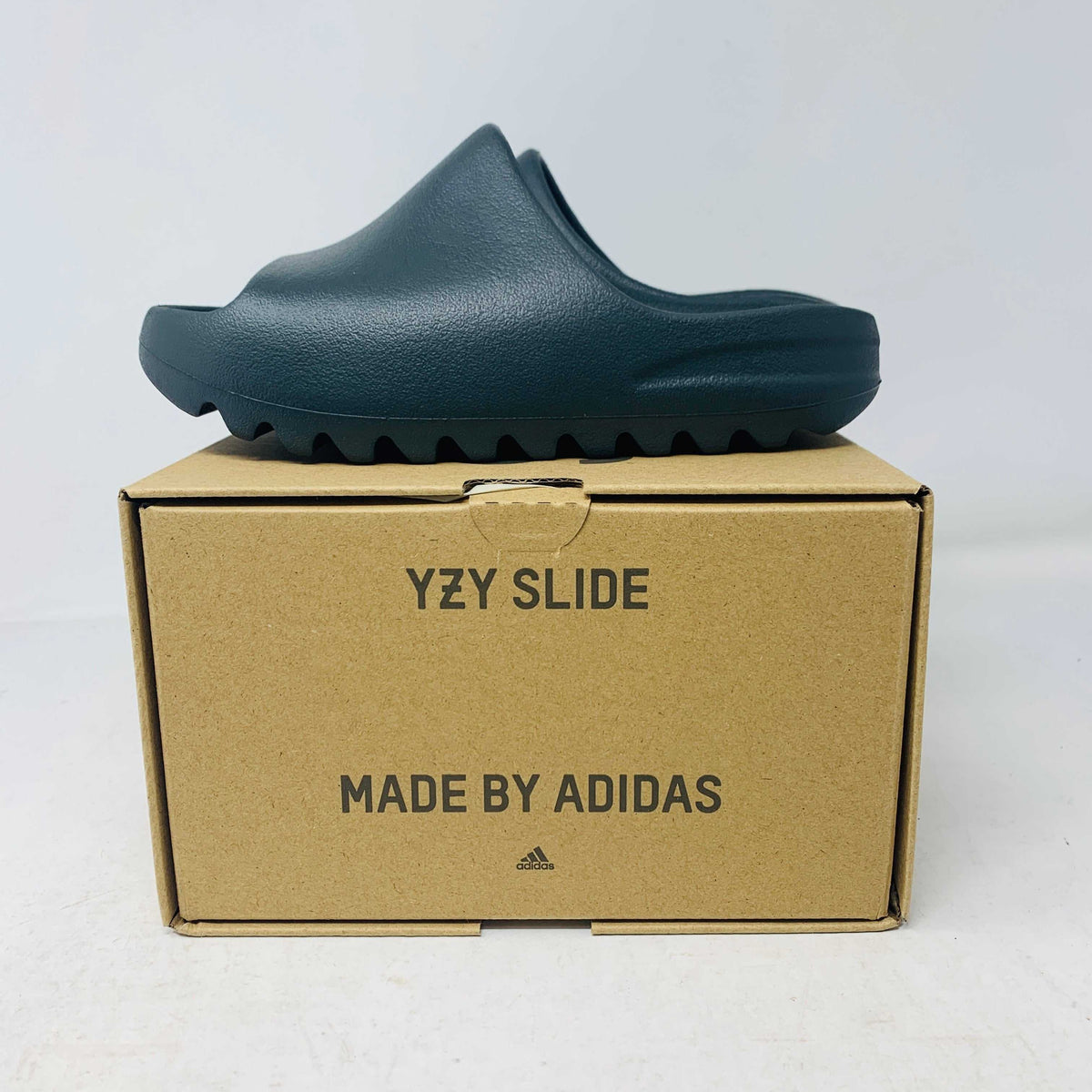 adidas Yeezy Slide in dark onyx color with textured sole and minimalist design, displayed on branded cardboard box