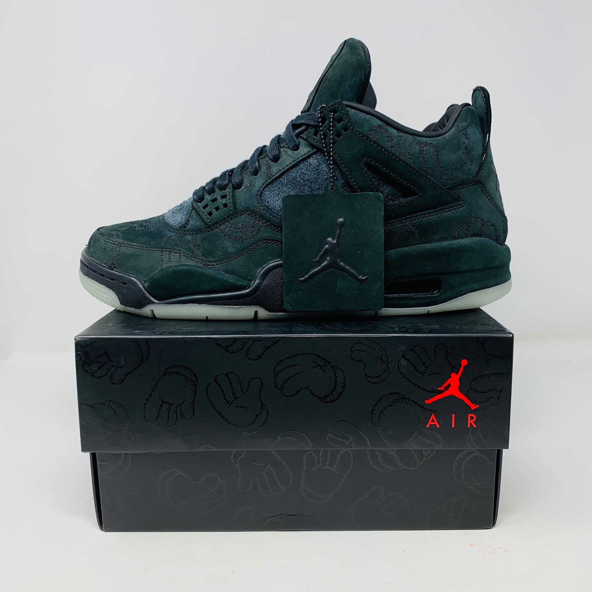 Jordan 4 Retro Kaws Black sneaker on original box with KAWS-inspired design and logo tag