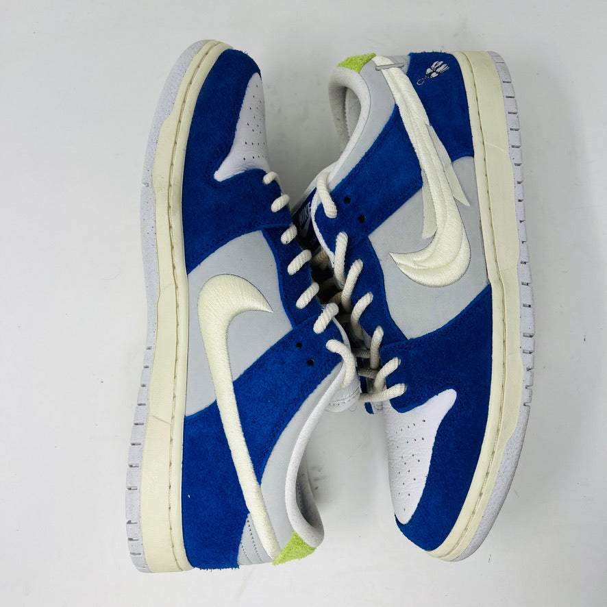 The Nike SB Dunk Low Pro Fly Streetwear Gardenia sneakers feature an authentic blue and gray design with white laces and swoosh logos. They include white soles, a green heel tab accent, and are presented on a plain white background. All sales are final; no returns accepted.