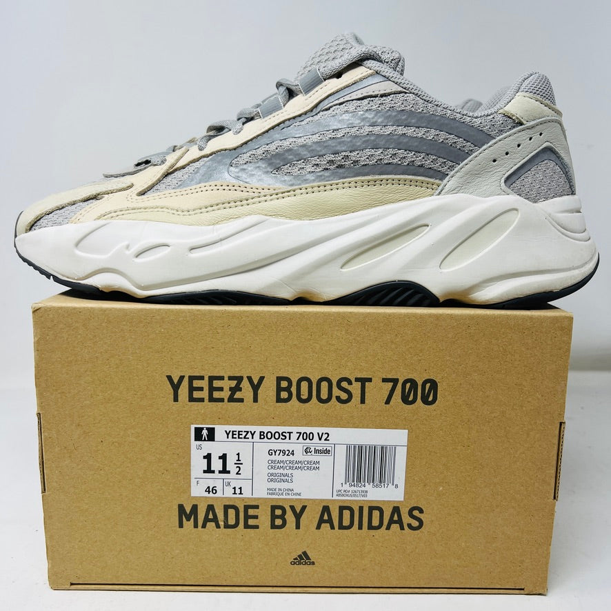 Adidas Yeezy Boost 700 V2 Cream sneakers in beige, gray, and white rest on a brown box labeled Yeezy Boost 700, Made by Adidas, showing minor wear. Box size label: 11.5.