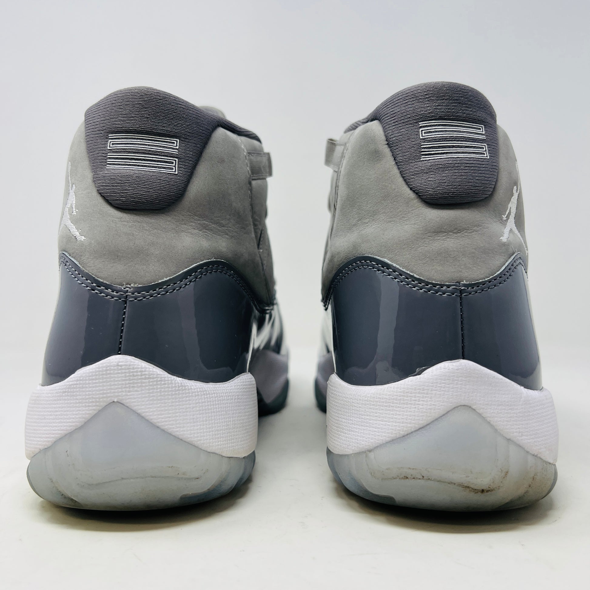 The Jordan 11 Retro Cool Grey (2021) sneaker, featuring clean gray and white uppers with glossy patent leather accents and white laces, is displayed on a gray Nike Air shoebox. The shoe is authentic in size 9.5, with the box in good condition.