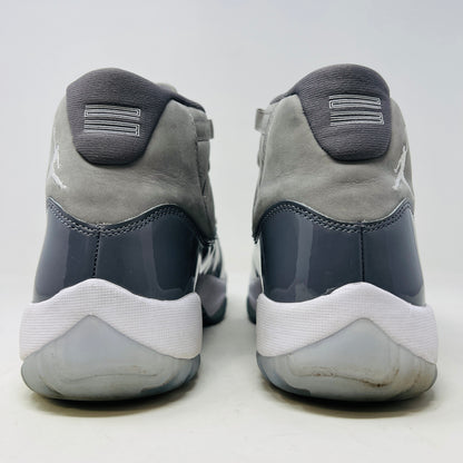 The Jordan 11 Retro Cool Grey (2021) sneaker, featuring clean gray and white uppers with glossy patent leather accents and white laces, is displayed on a gray Nike Air shoebox. The shoe is authentic in size 9.5, with the box in good condition.