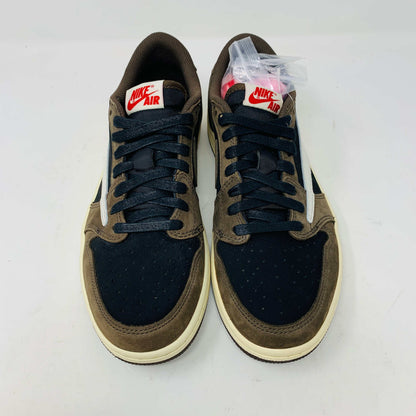 A pair of BRAND NEW Jordan 1 Low OG Travis Scott Mocha sneakers in black and brown, featuring a white swoosh, displayed on a brown shoe box with a red logo. 100% Authentic with EXTRA LACES partially visible inside.