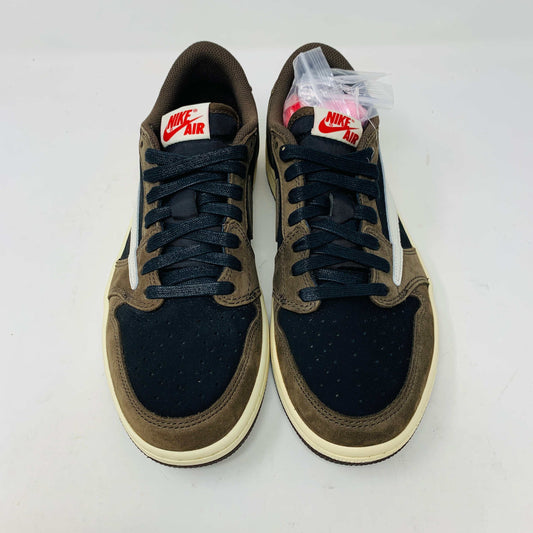 A pair of BRAND NEW Jordan 1 Low OG Travis Scott Mocha sneakers in black and brown, featuring a white swoosh, displayed on a brown shoe box with a red logo. 100% Authentic with EXTRA LACES partially visible inside.