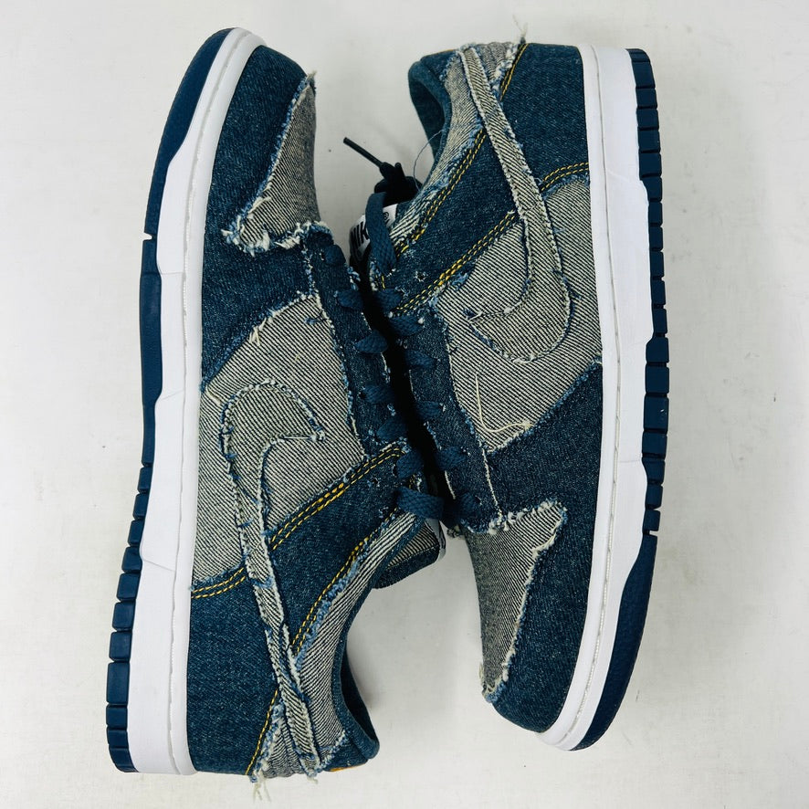 Side view of a brand new Nike Dunk Low CL Denim sneaker with white accents, resting on its orange box. A label reads Denim Dunk. Released in 2006, it features a textured design with a white midsole and blue outsole. Box condition is pristine. Brand: Nike.