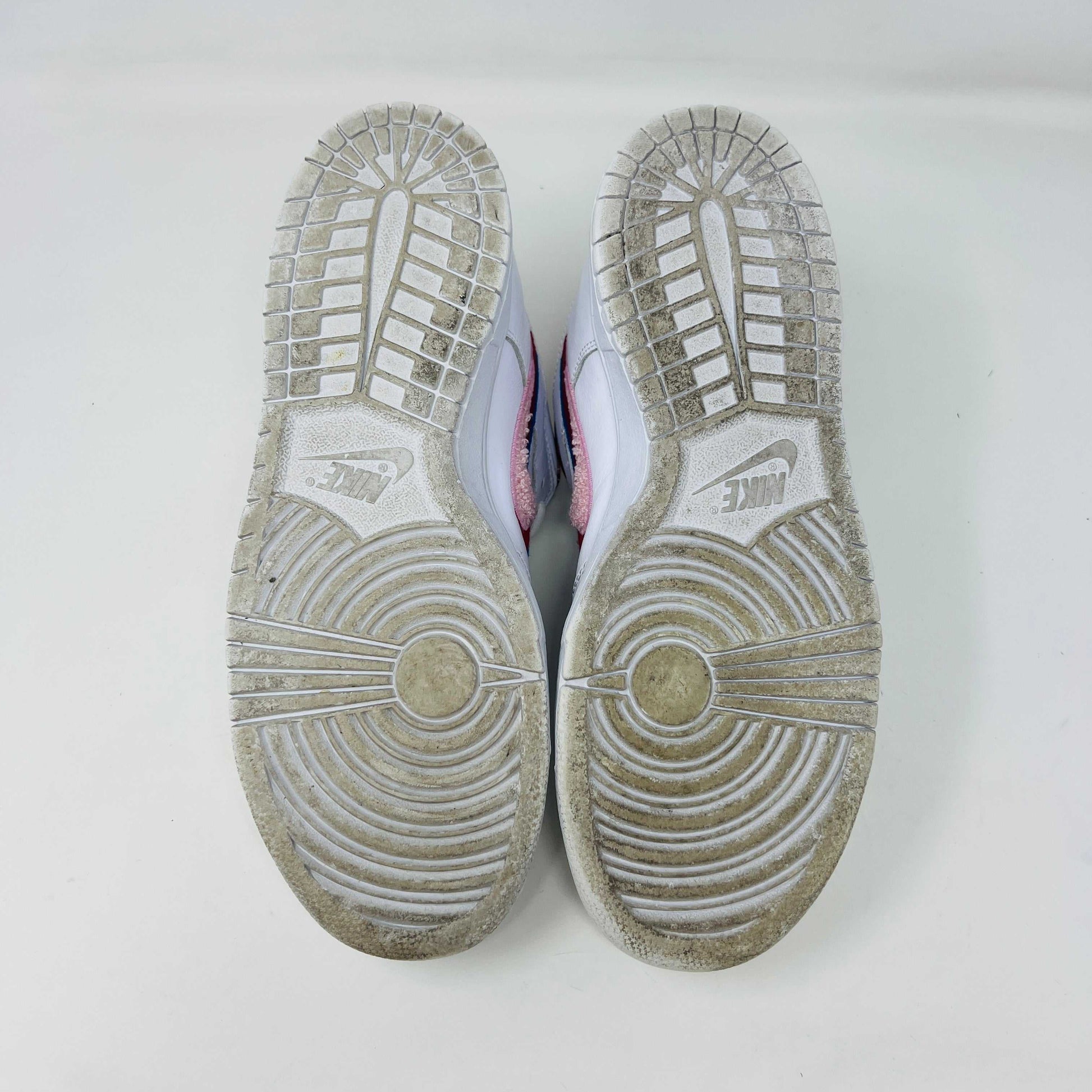 A white Nike SB Dunk Low Parra from 2019 with a multicolored swoosh rests on a black and teal box. The authentic shoes feature clean uppers, size 10.5, as indicated on the label.