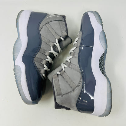 The Jordan 11 Retro Cool Grey (2021) sneaker, featuring clean gray and white uppers with glossy patent leather accents and white laces, is displayed on a gray Nike Air shoebox. The shoe is authentic in size 9.5, with the box in good condition.