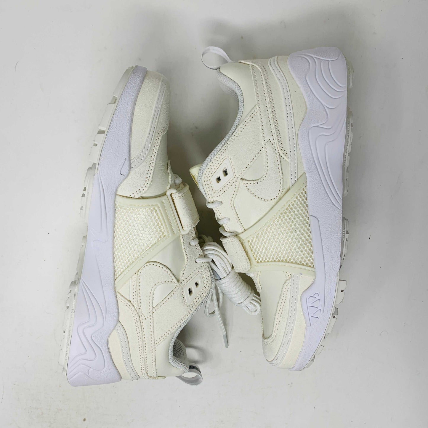 A pair of brand new, 100% authentic Nike Zoom Field Jaxx SP Travis Scott Sail sneakers feature a white colorway with a textured design and lace-up closure. The shoes, shown on a white background, have a thick sole and combine smooth and perforated panels.