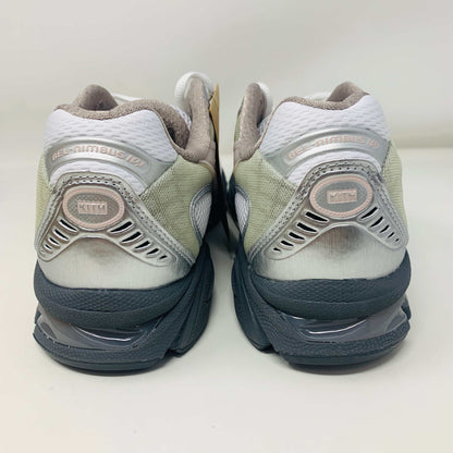 The ASICS Gel-Nimbus 10.1 Kith White Morganite features white, gray, and light pink tones displayed on a shoebox. Includes two sets of laces: one brand new in white with black specks and one plain beige, sealed in plastic bags, ready for 2024.