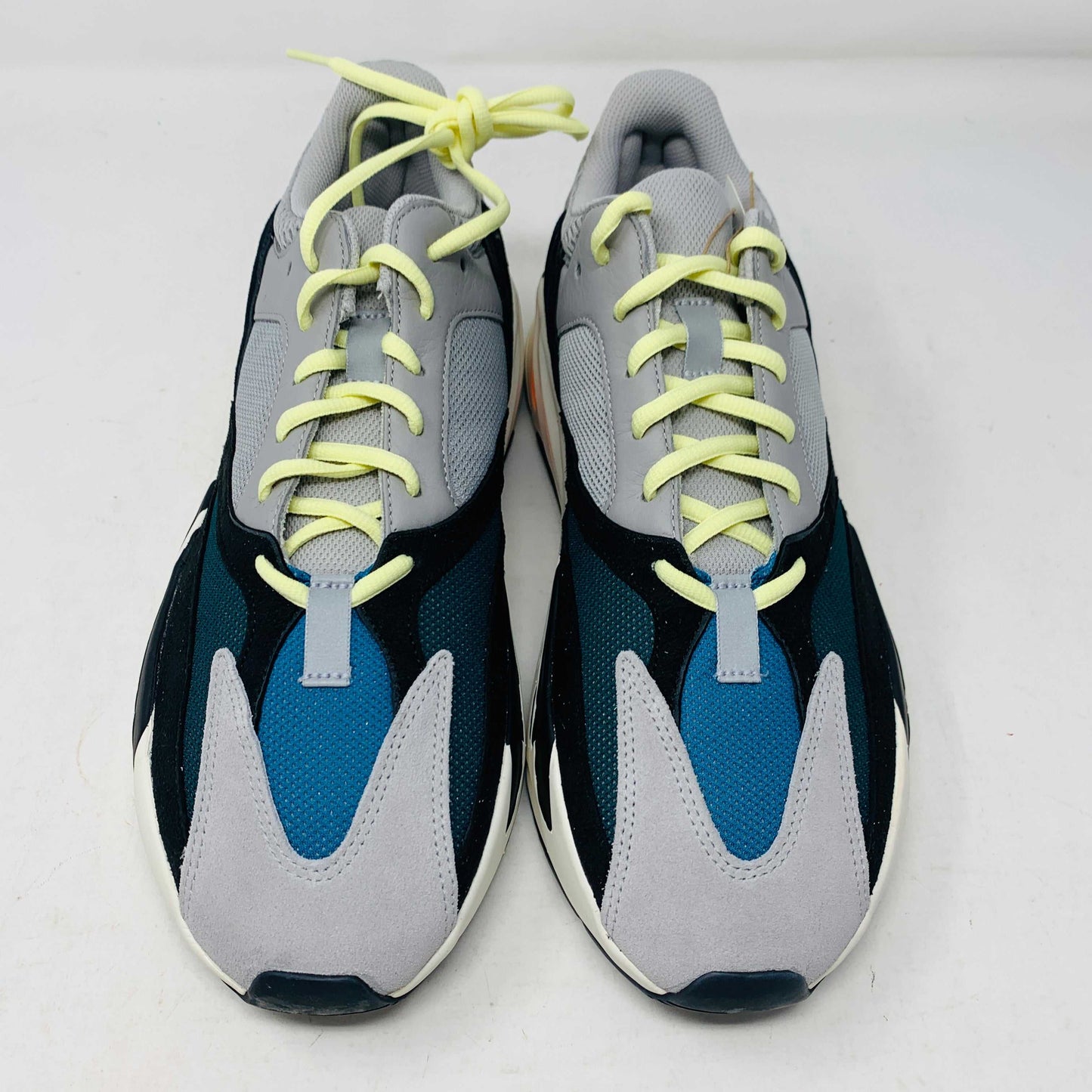 A Yeezy 700 Waverunner with a multicolor scheme of gray, black, teal, and orange rests on a Yeezy Boost 700 Made by Adidas box. Sales are final on these authentic shoes.