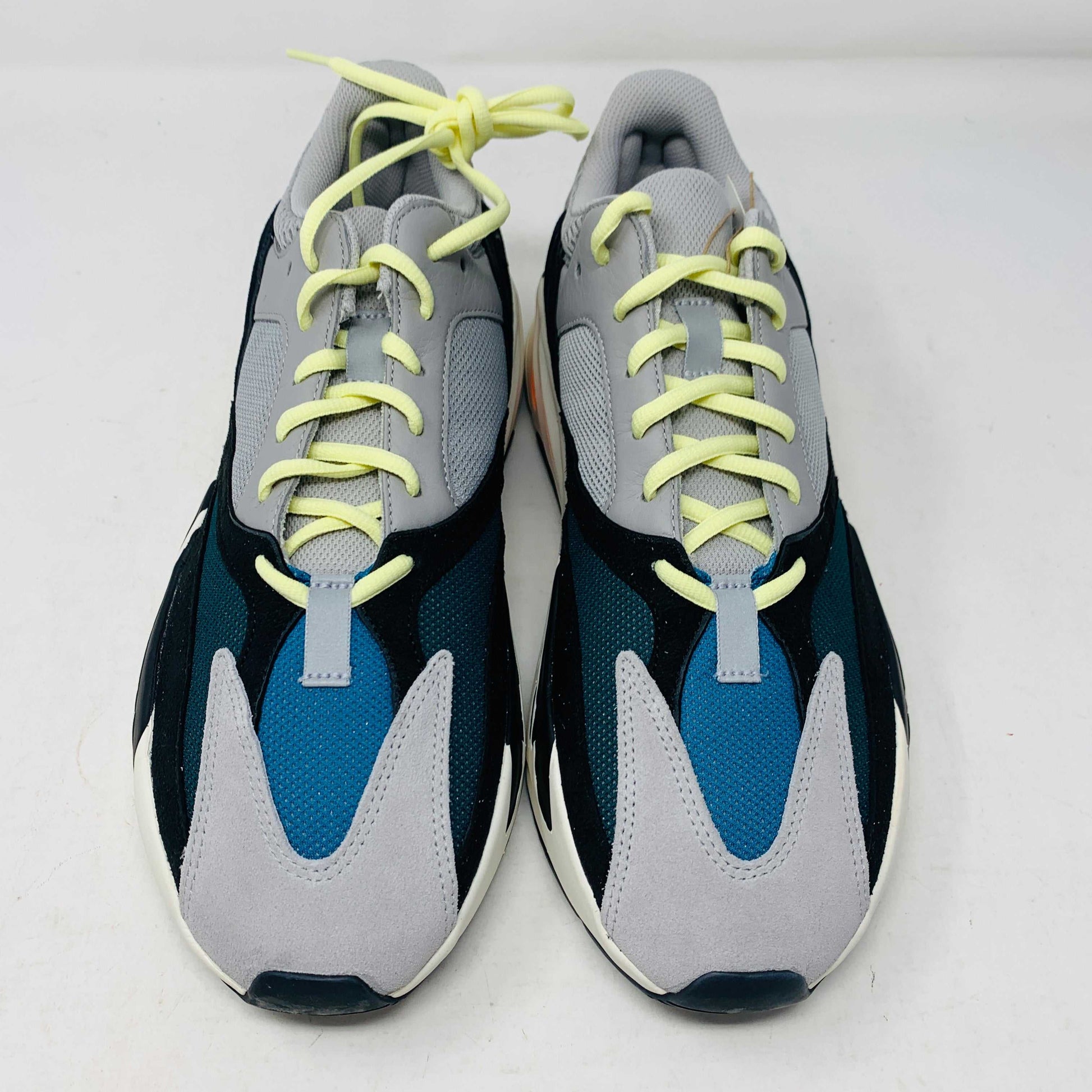 A Yeezy 700 Waverunner with a multicolor scheme of gray, black, teal, and orange rests on a Yeezy Boost 700 Made by Adidas box. Sales are final on these authentic shoes.