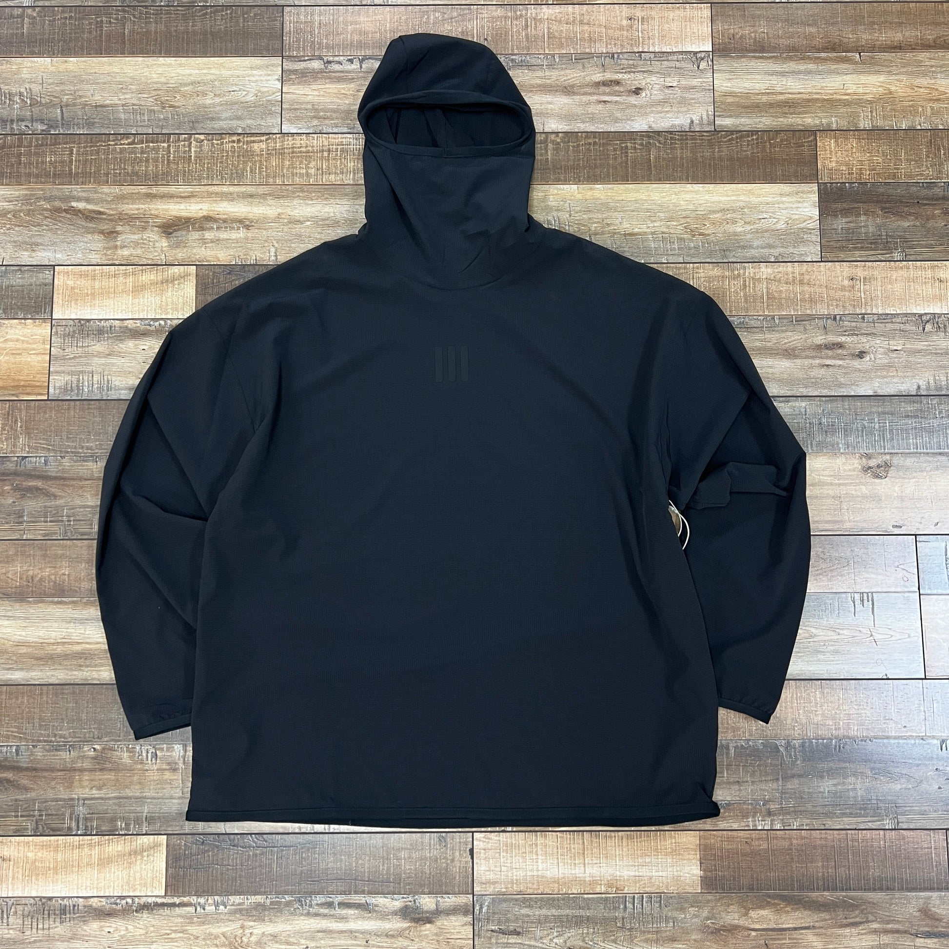 Fear of God Athletics Adidas black stretch woven running hoodie laid flat on wooden floor
