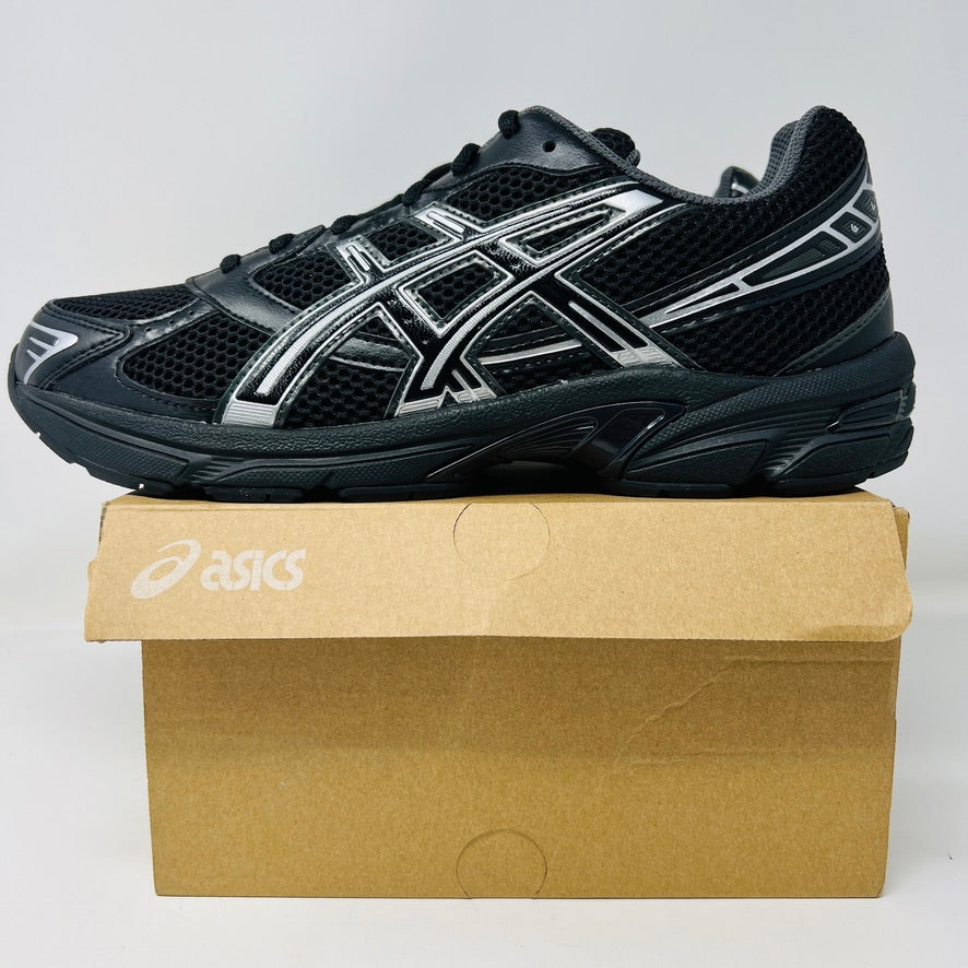 The ASICS Gel-1130 Black Pure Silver athletic shoe, in brand new condition, is showcased on a light brown ASICS shoe box against a crisp white background.