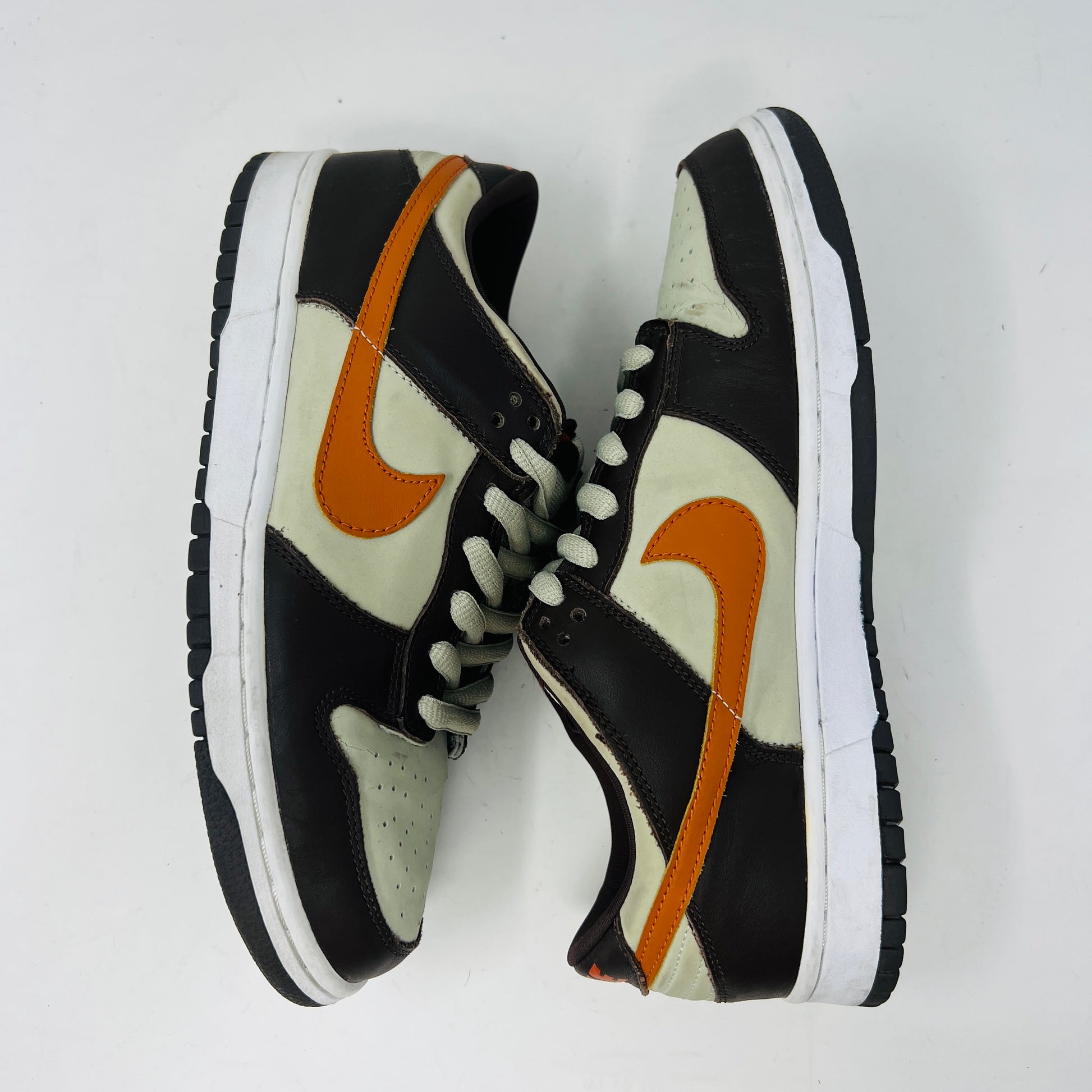 The Nike Dunk Low Pro B Light Stone Mesa Orange sneaker from 2002 is shown side-on, featuring sleek uppers in dark brown and cream with an orange swoosh. It rests elegantly on a white midsole with a black outsole against a plain background.
