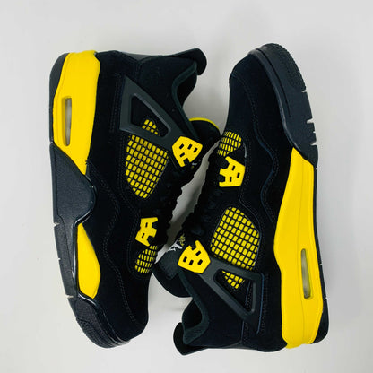 Brand new for 2023, the Jordan 4 Retro Thunder (GS) sneakers in black and yellow feature mesh panels and air cushioning. Positioned on a white background, they showcase their unique color scheme and design.