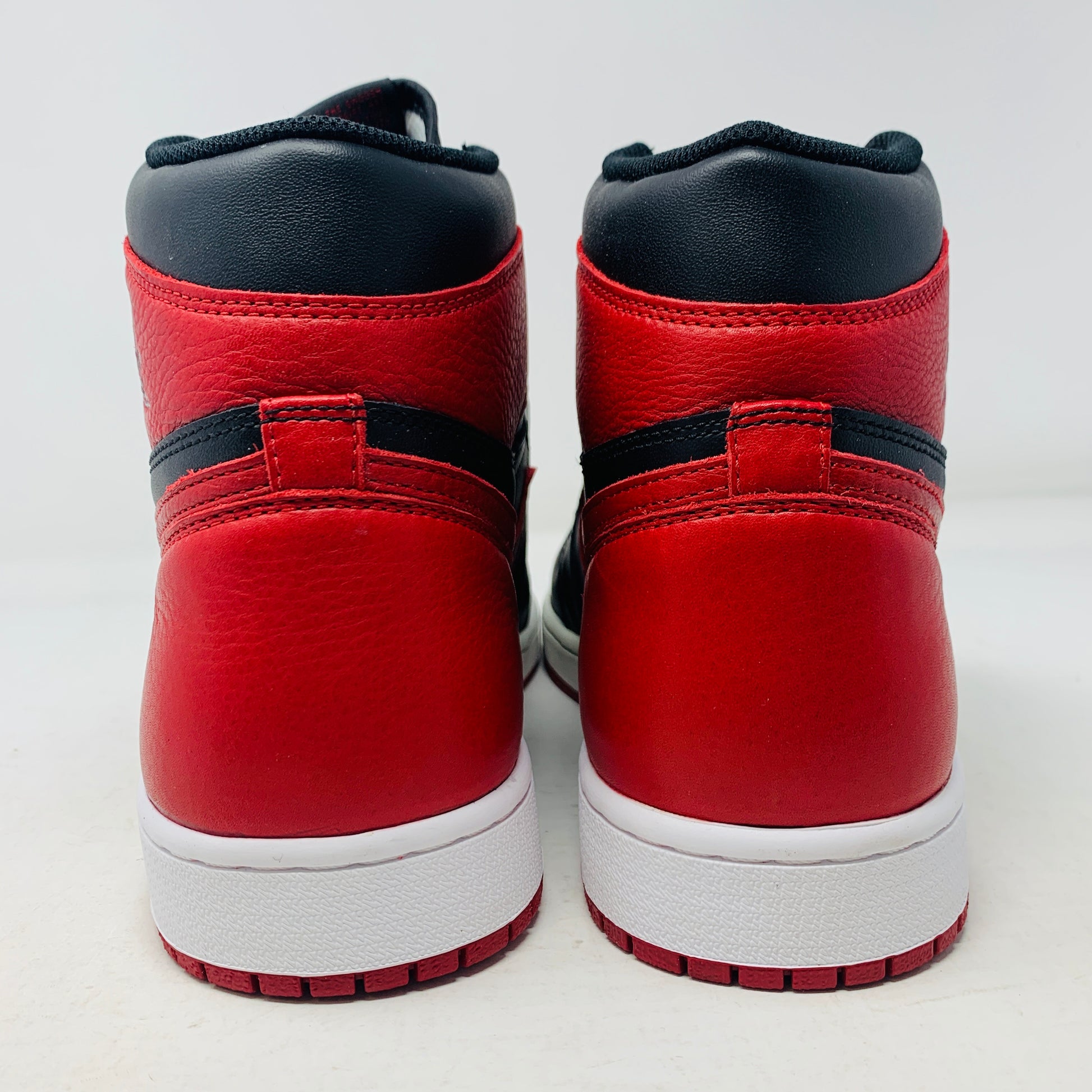 The Jordan 1 High Bred 2016 sneakers, by Jordan, are brand-new black and red high-tops with a white sole. Viewed from above, they showcase an unlaced look with a perforated design on the toe area.