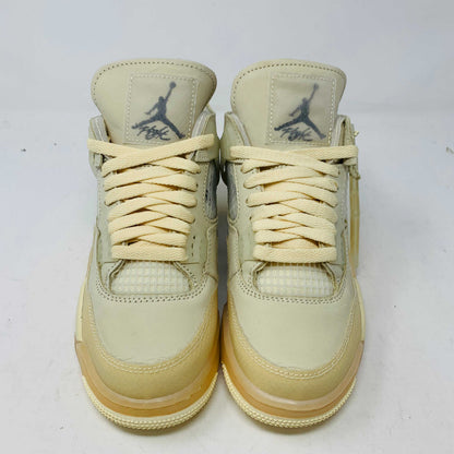 A beige Jordan 4 Off White Sail W sneaker rests on a box with the authentic Air Jordan logo. It comes with three extra sets of laces in mint, cream, and black labeled SHOELACES, a plastic zip tie, and features a small Jumpman Air tag.