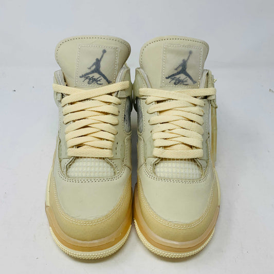 A beige Jordan 4 Off White Sail W sneaker rests on a box with the authentic Air Jordan logo. It comes with three extra sets of laces in mint, cream, and black labeled SHOELACES, a plastic zip tie, and features a small Jumpman Air tag.