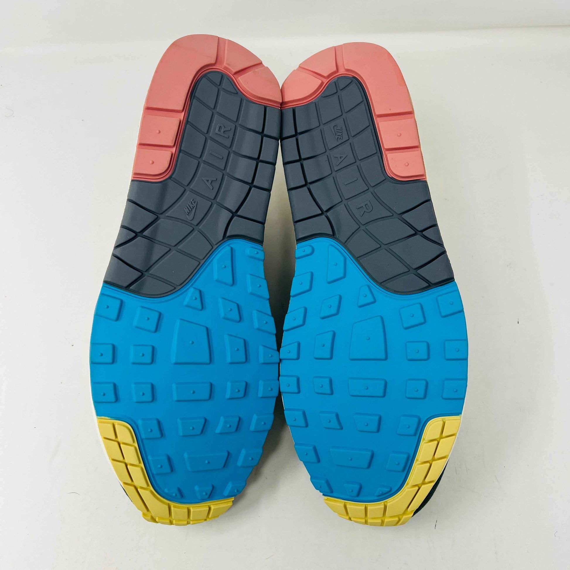 Nike Air Max 1/97 SW Sean Wotherspoon sneakers are displayed on a red Nike box, with authentic extra blue and yellow laces in plastic bags in front. The brand-new shoes feature a wave-like design with vibrant colors.