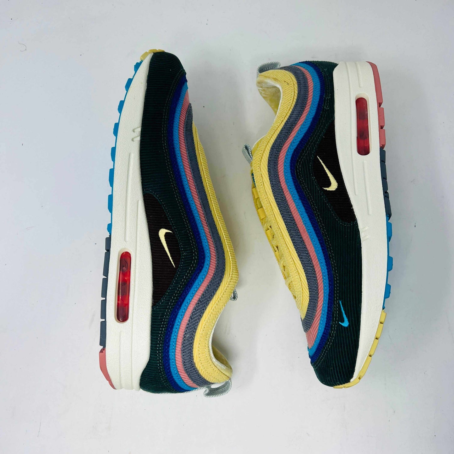 Nike Air Max 1/97 SW Sean Wotherspoon sneakers are displayed on a red Nike box, with authentic extra blue and yellow laces in plastic bags in front. The brand-new shoes feature a wave-like design with vibrant colors.