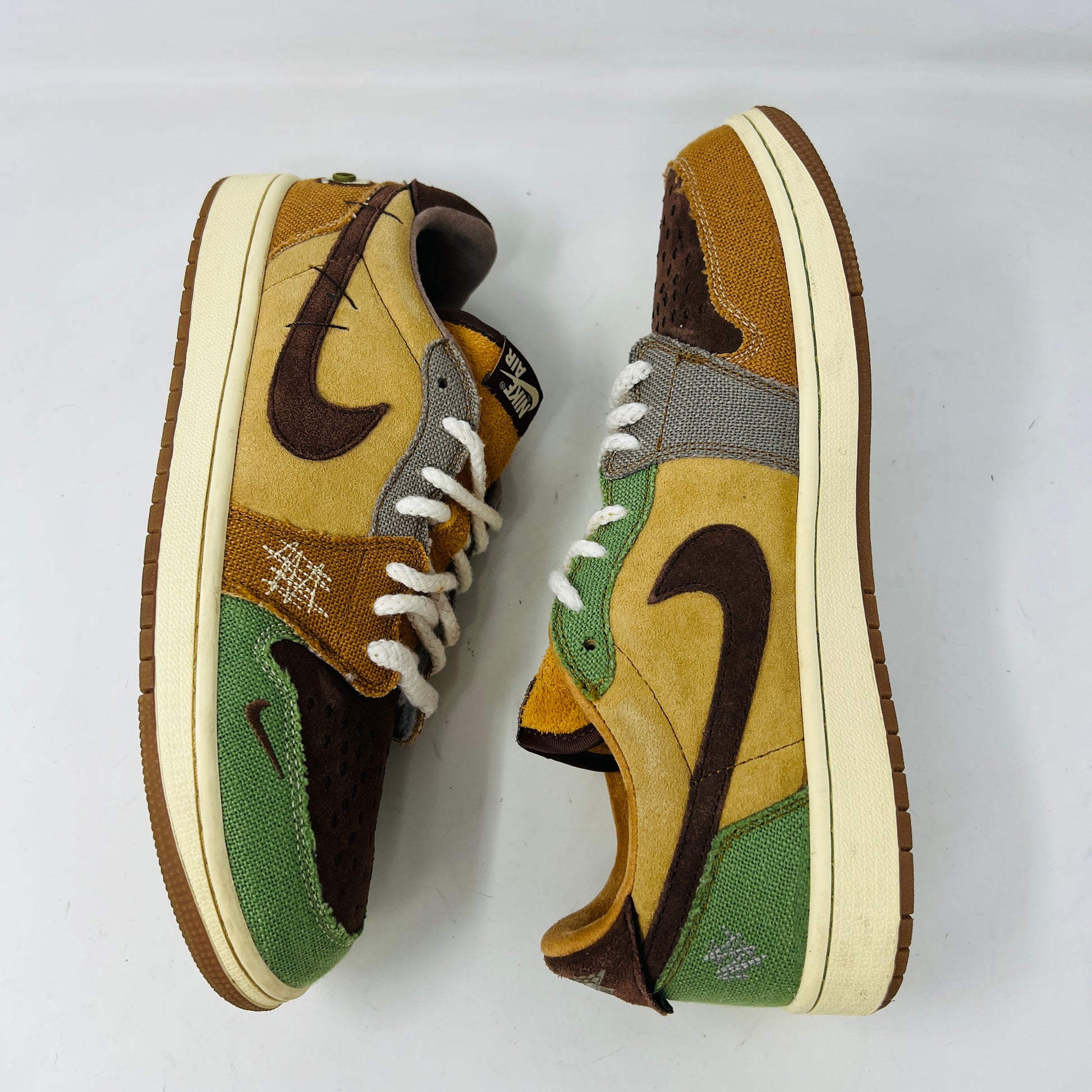 Multicolored Jordan 1 Retro Low OG Zion Williamson Voodoo sneakers feature a patchwork design and visible stitching with brown, yellow, and green sections. The stylish kicks have clean uppers with minimal heel drag, set elegantly on a purple box displaying size and price labels.