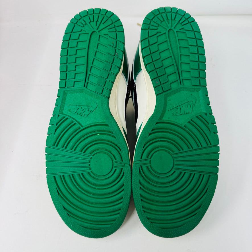 The Nike Dunk Low SE Lottery Pack Malachite Green sneaker, from the 2022 collection, is displayed on a red Nike shoebox. It features clean green and white uppers, a black swoosh logo, and a white midsole. The partially open lid shows essential shoe information and size labels.