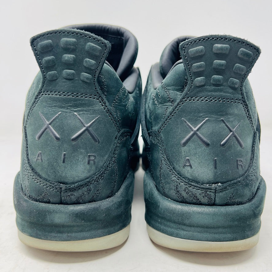 A dark green suede sneaker with a textured design, reminiscent of OG ALL styles, sits atop a matching box. Tagged size 10.5, it features a small red Jumpman logo and includes a XX AIR keychain from its 2017 release. Product: Jordan 4 Retro Kaws Black by Jordan.