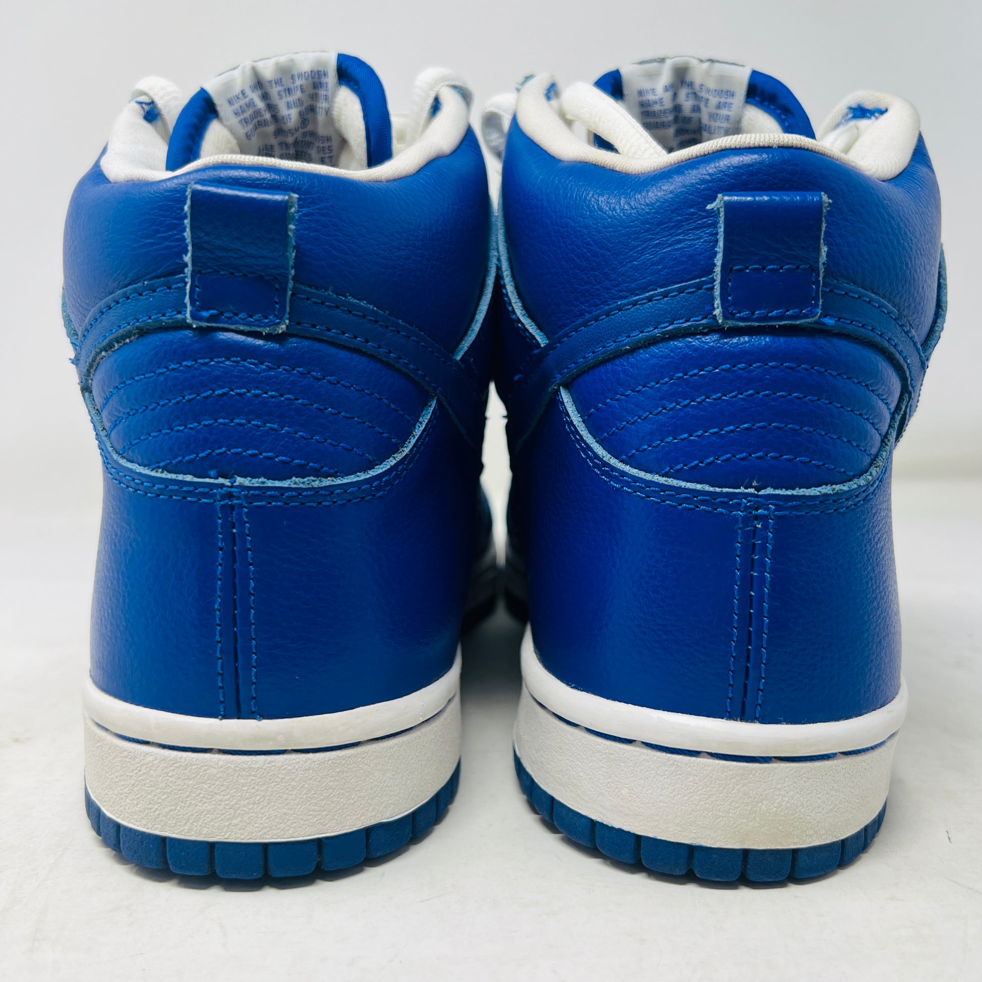A Nike SB Dunk High T19 Royal Blue sneaker with white laces is perched on a pristine pink shoebox, showcasing the iconic Nike swoosh. The box, in excellent condition, displays a size 10 label.