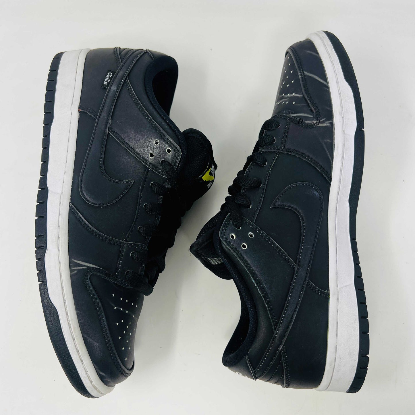 Nike SB Dunk Low Civilist sneakers, black with white soles and yellow tongue details, showcased on a white backdrop. They blend style and comfort effortlessly, making them a standout in 2020 sneaker collections.