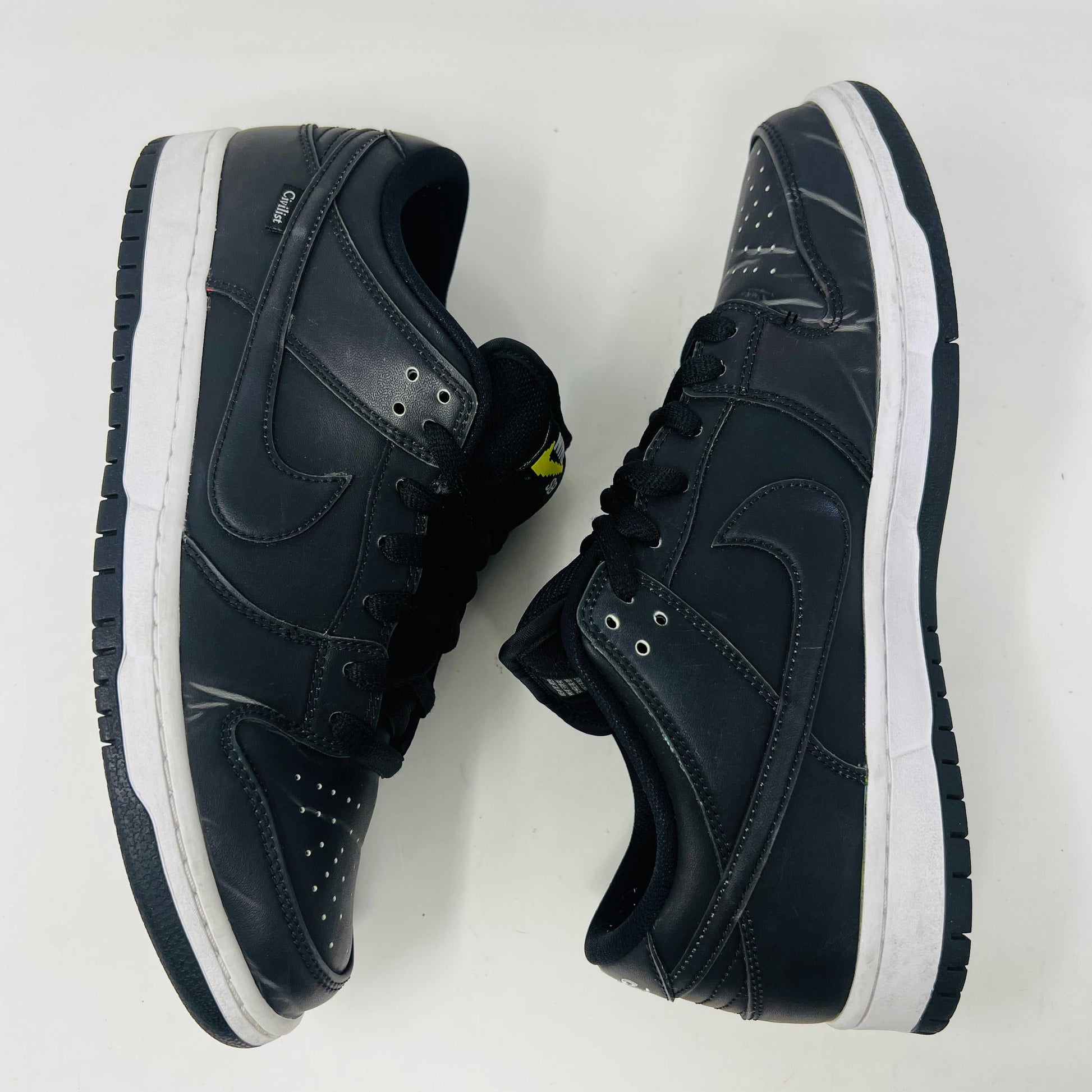 Nike SB Dunk Low Civilist sneakers, black with white soles and yellow tongue details, showcased on a white backdrop. They blend style and comfort effortlessly, making them a standout in 2020 sneaker collections.