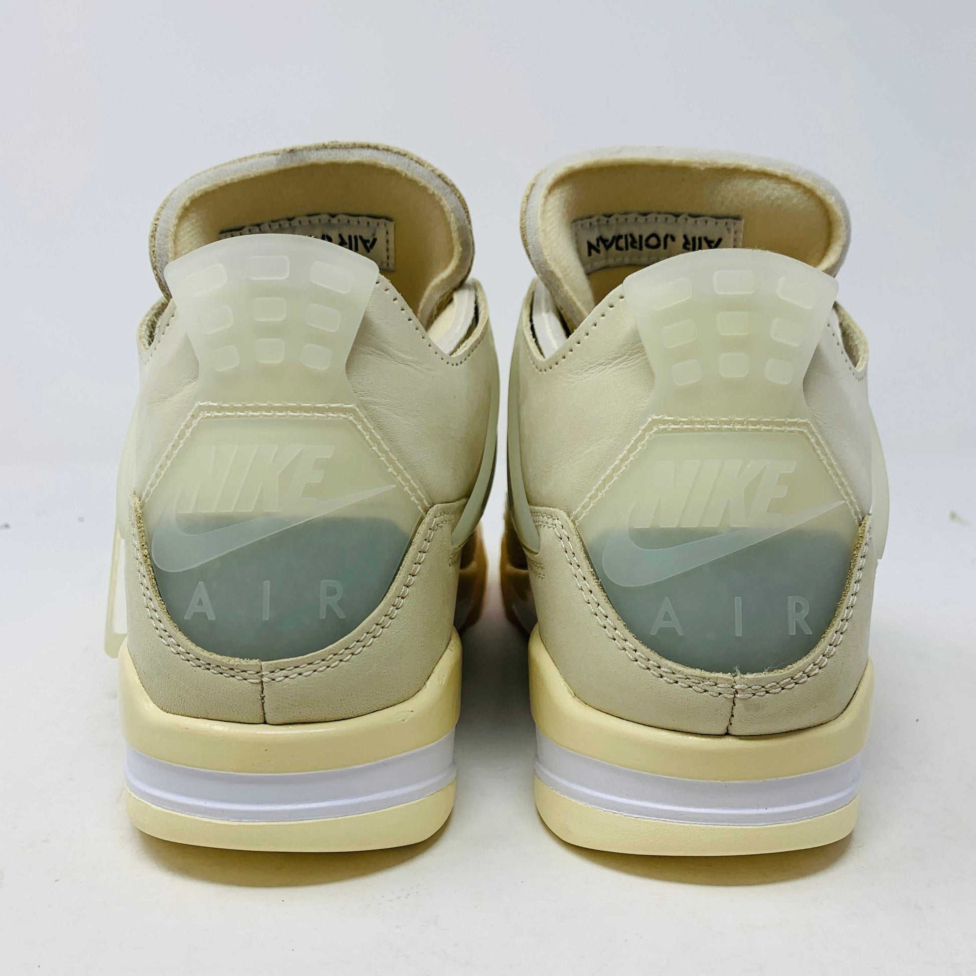 A beige Jordan 4 Off White Sail W sneaker rests on a box with the authentic Air Jordan logo. It comes with three extra sets of laces in mint, cream, and black labeled SHOELACES, a plastic zip tie, and features a small Jumpman Air tag.