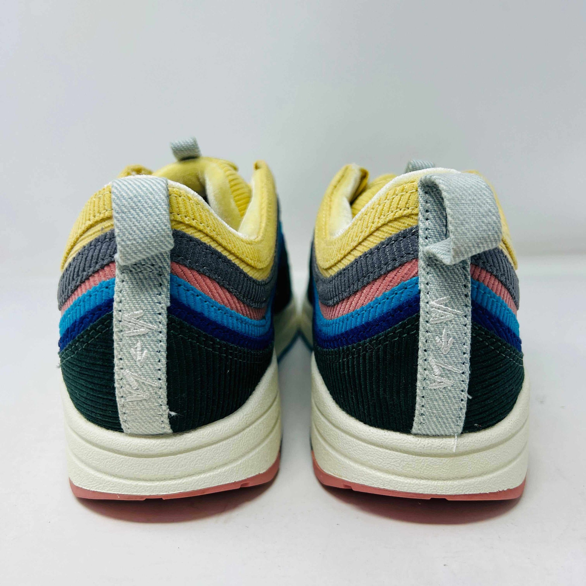 Nike Air Max 1/97 SW Sean Wotherspoon sneakers are displayed on a red Nike box, with authentic extra blue and yellow laces in plastic bags in front. The brand-new shoes feature a wave-like design with vibrant colors.