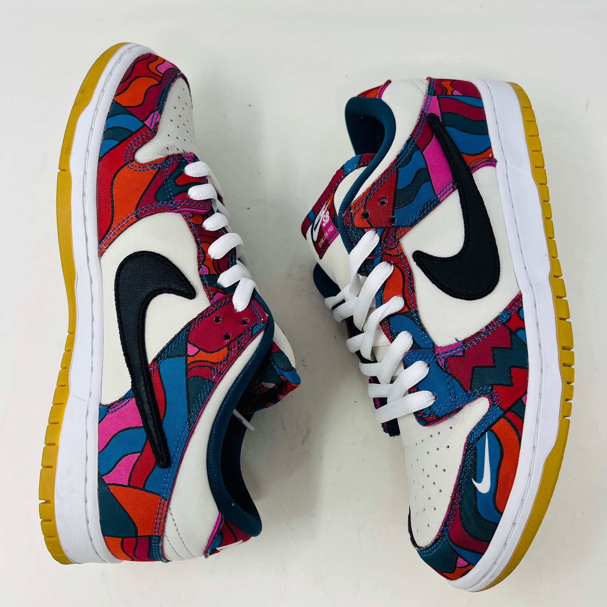 The Nike SB Dunk Low Pro Parra Abstract Art (2021) features a colorful design with abstract red, blue, and purple patterns on a white base. It includes clean uppers with a black swoosh, white laces, and comes in a green/yellow box with extra blue laces for added versatility.