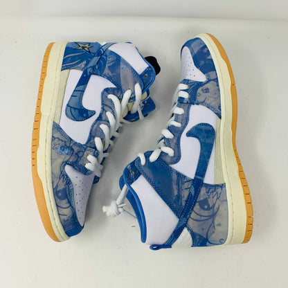 The Nike SB Dunk High Carpet Company sneakers feature a blue and white starry design, presented on a green and yellow Nike shoe box. Three extra laces in blue, yellow, and white are included to ensure your style is 100% authentic.