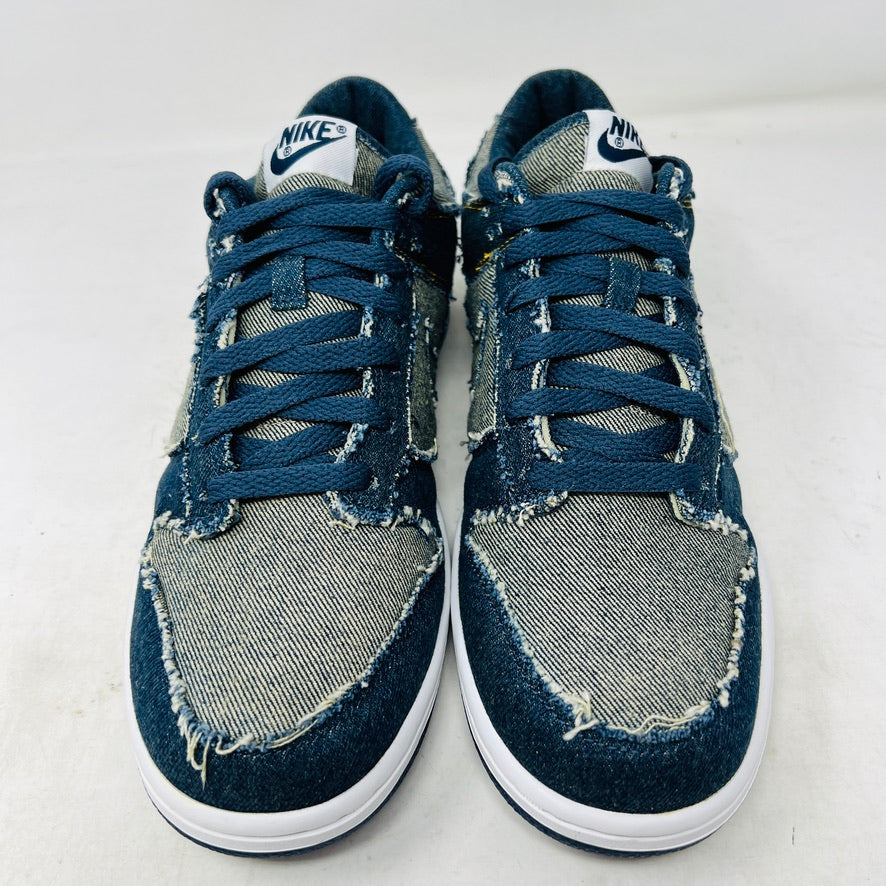 Side view of a brand new Nike Dunk Low CL Denim sneaker with white accents, resting on its orange box. A label reads Denim Dunk. Released in 2006, it features a textured design with a white midsole and blue outsole. Box condition is pristine. Brand: Nike.