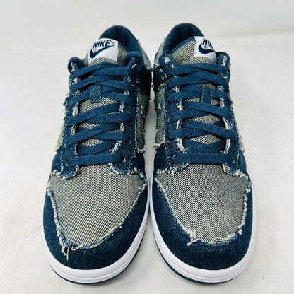 Side view of a brand new Nike Dunk Low CL Denim sneaker with white accents, resting on its orange box. A label reads Denim Dunk. Released in 2006, it features a textured design with a white midsole and blue outsole. Box condition is pristine. Brand: Nike.