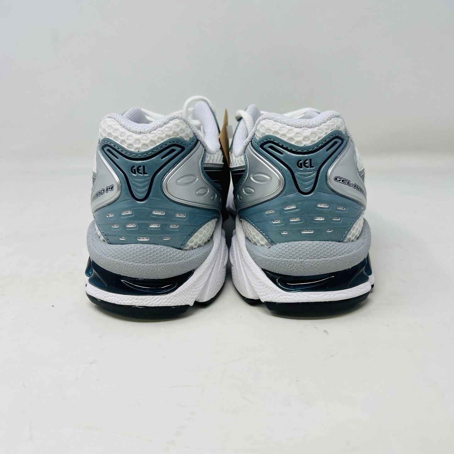 The ASICS Gel-Kayano 14 White Fjord Grey running shoe stands on a brown ASICS box, featuring intricate designs, a breathable mesh upper, and a cushioned thick sole for support. Its 100% authentic.