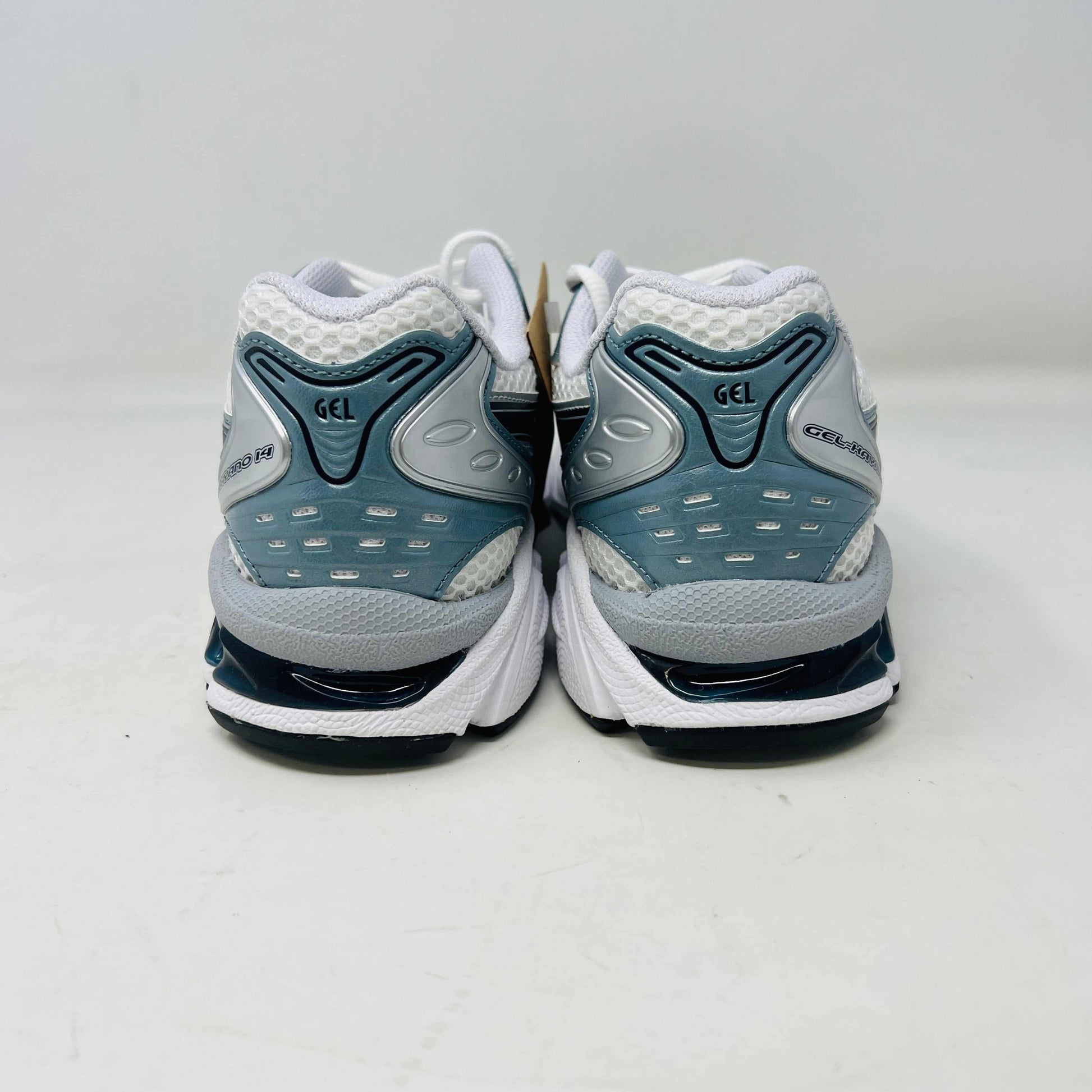 The ASICS Gel-Kayano 14 White Fjord Grey running shoe stands on a brown ASICS box, featuring intricate designs, a breathable mesh upper, and a cushioned thick sole for support. Its 100% authentic.