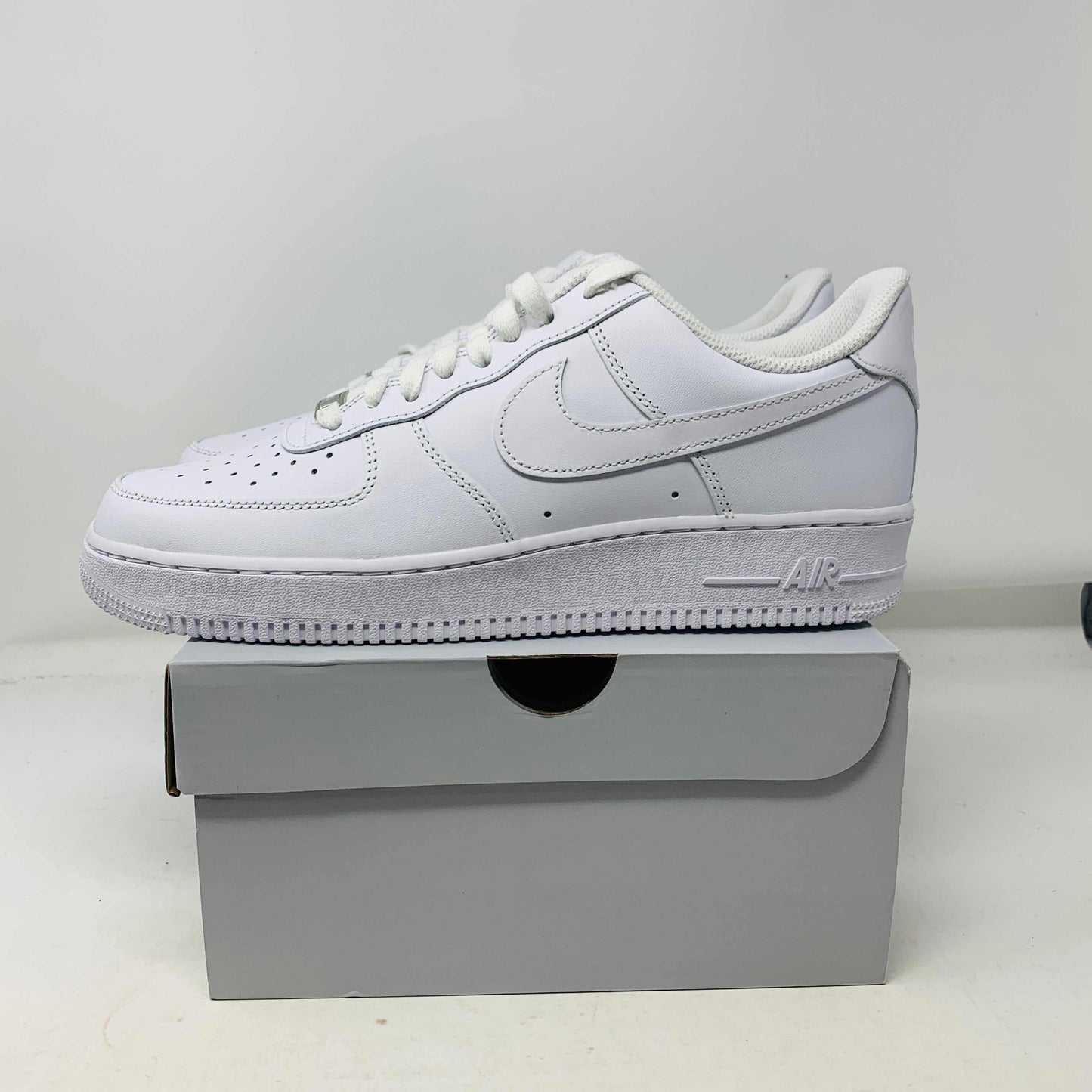 Nike Air Force 1 Low Triple White sneakers, brand new condition, on a shoe box.